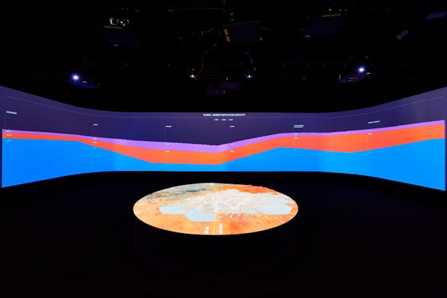 An infographic of global population growth fills the walls of the gallery.